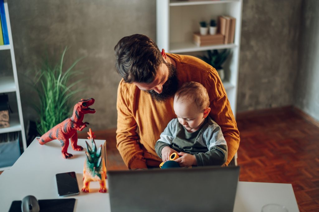 Man sitting with baby in lap in front of computer