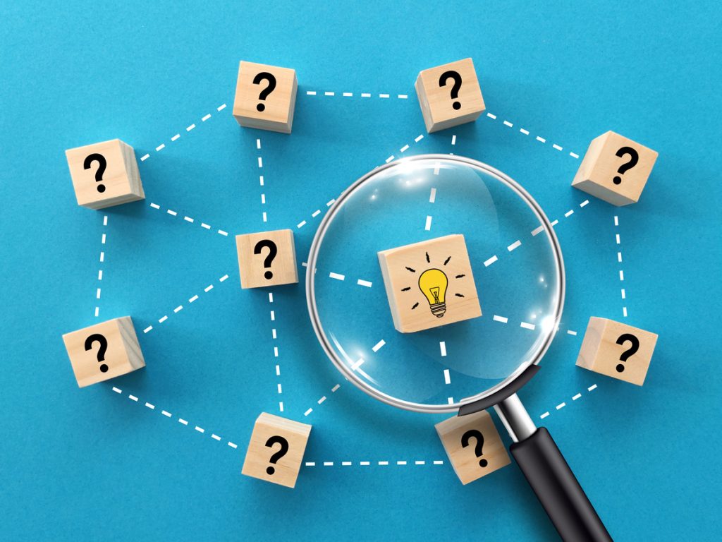 magnifying glass and light bulb icons on wooden blocks with blue background