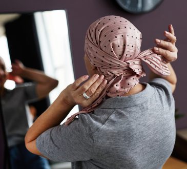 Woman looking in mirror tying headscarf