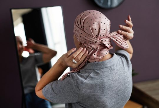 Woman looking in mirror tying headscarf