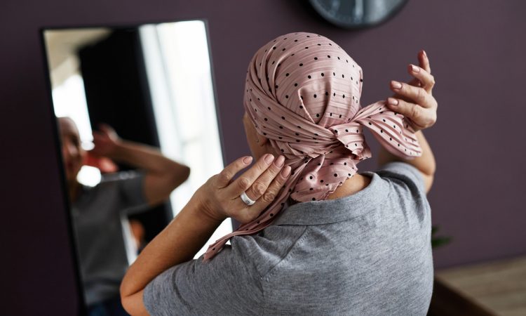 Woman looking in mirror tying headscarf