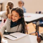 Child sitting in elementary school classroom, smiling