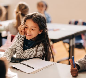 Child sitting in elementary school classroom, smiling