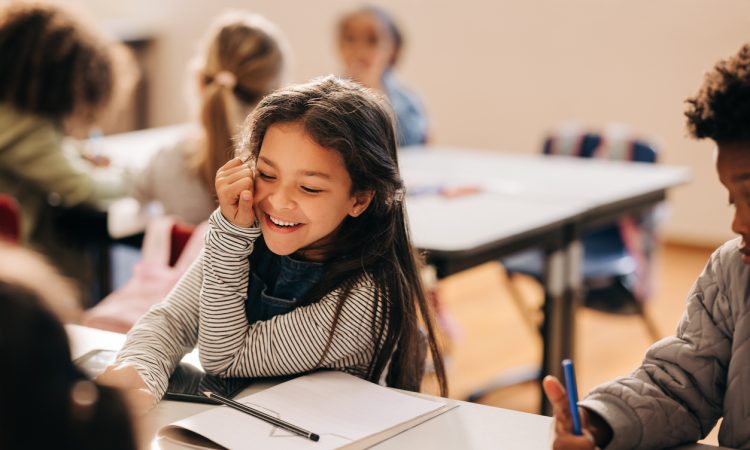 Child sitting in elementary school classroom, smiling