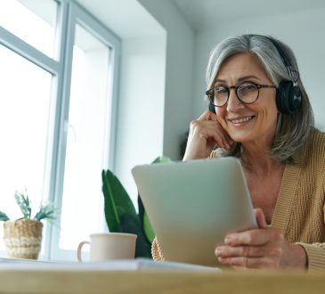 Woman smiling, sitting and watching something on tablet screen