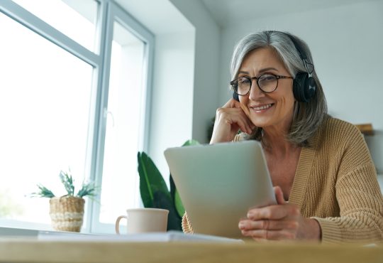 Woman smiling, sitting and watching something on tablet screen