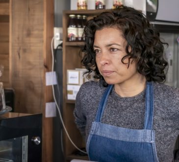 Waitress wearing apron standing behind bar