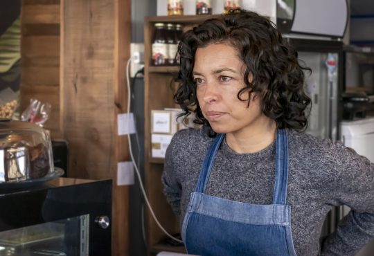 Waitress wearing apron standing behind bar