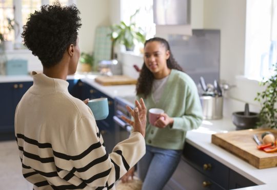 Mother Talking With Teenage Daughter At Home In Kitchen