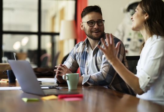 Two people sitting and talking at work.