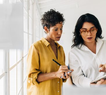 Two women standing and talking in office.