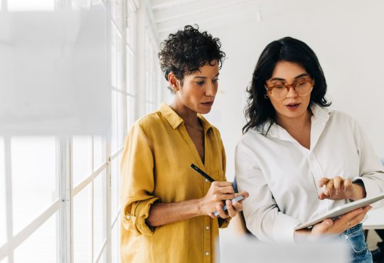 Two women standing and talking in office.