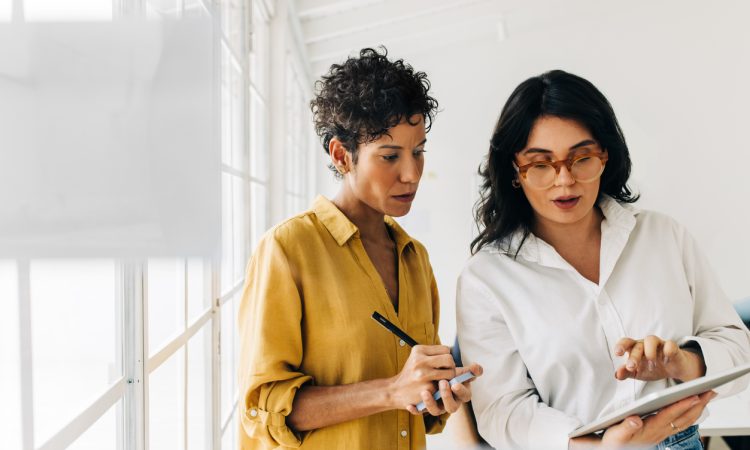 Two women standing and talking in office.