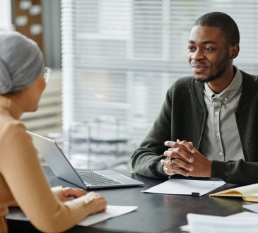 Two people sitting across desk from each other in job interview in office