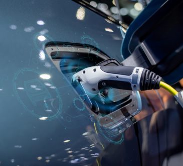 The image shows an electric vehicle charging at a charging station, with a close-up of the charging plug inserted into the vehicle and digital graphics overlaying the scene, suggesting technology and connectivity.