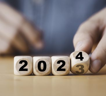 Hand flipping of 2023 to 2024 on wooden block cube.
