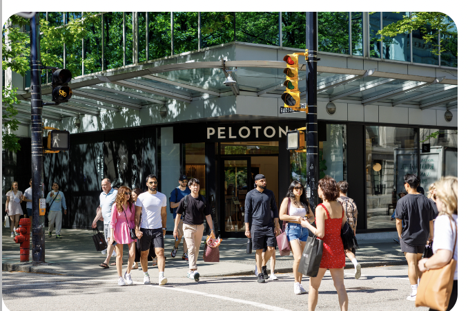 Photo of a busy street corner intersection with many people walking.