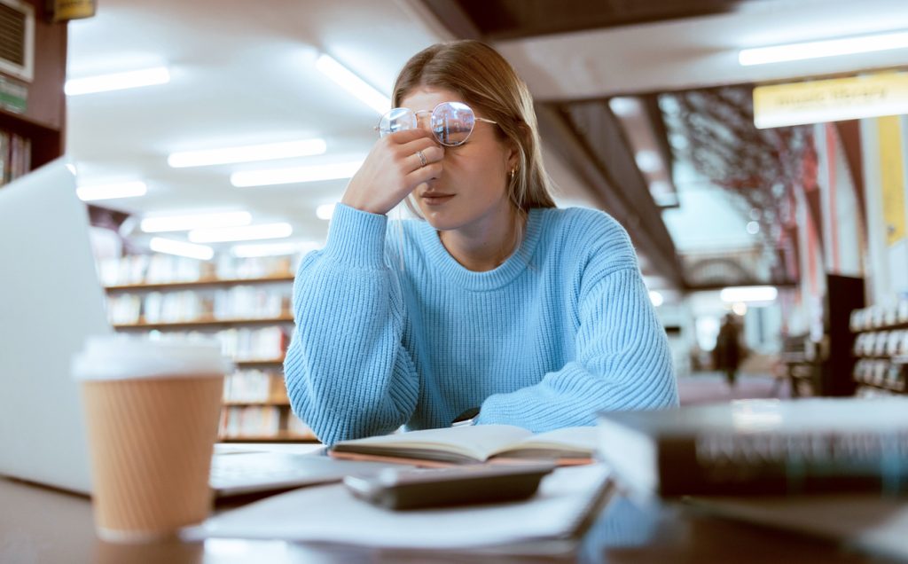 University student in library with head in hand