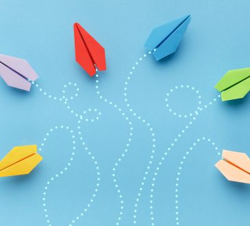 Colourful paper plans on blue background with routes traced in dotted white lines