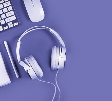 Purple background with white keyboard, notebook, headphones and mouse