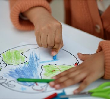 Close up of hands of child colouring picture of Earth