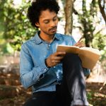 Man writing in journal outdoors