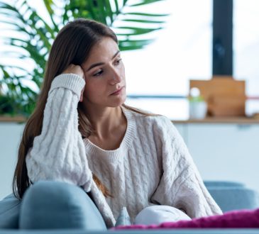Shot of depressed young woman thinking about her problems while sitting on the sofa at home.