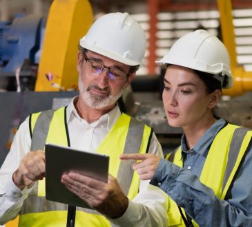 Senior manager on job training technician working in metal sheet production factory.