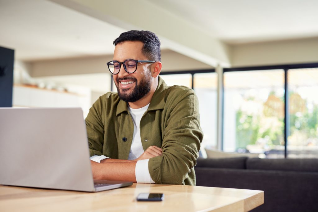 Man smiling while using laptop