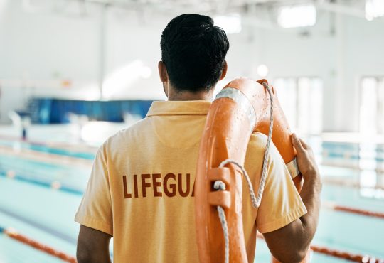 Lifeguard standing and facing pool