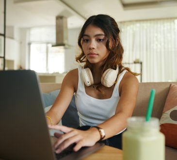 teenage girl with headphones working on laptop