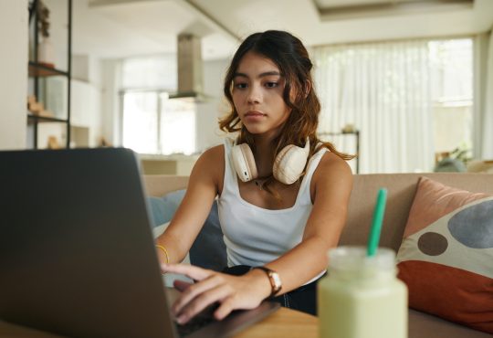 teenage girl with headphones working on laptop