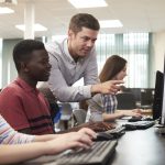 Teacher helping students in computer lab