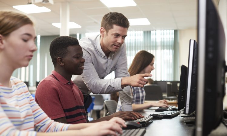 Teacher helping students in computer lab