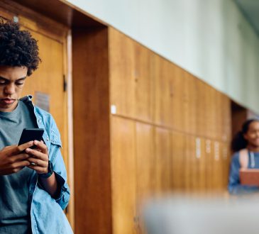 Teen texting in hallway of school