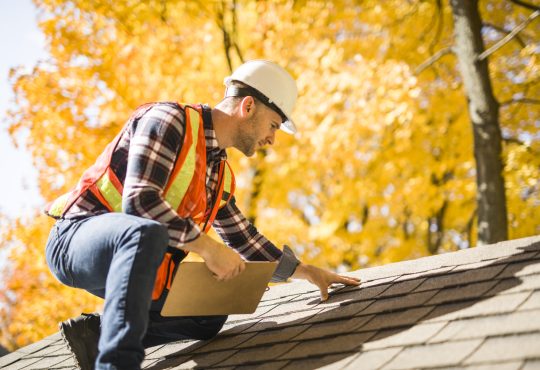 Man inspecting roof of house