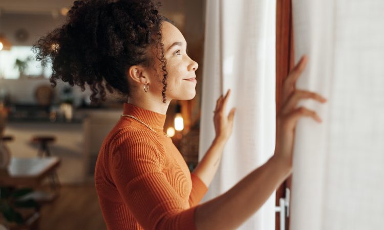 Curtains, happy woman and thinking of future in home, planning and reflection of mindset with view. Window, smile and African girl with vision, ideas and dream for morning inspiration in living room