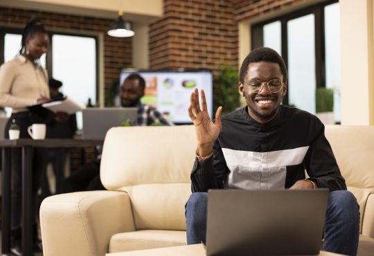 Black man waving towards laptop screen